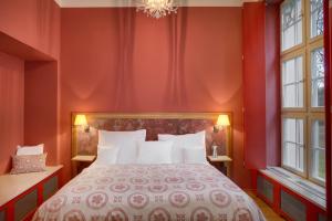 a bedroom with red walls and a bed with white pillows at Chateau Herálec Boutique Hotel & Spa by L'Occitane in Herálec