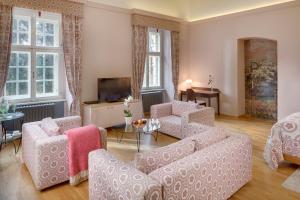 a living room with a couch and chairs and a tv at Chateau Herálec Boutique Hotel & Spa by L'Occitane in Herálec