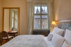 a hotel room with a bed and a window at Chateau Herálec Boutique Hotel & Spa by L'Occitane in Herálec