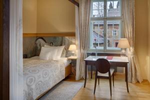 a bedroom with a bed and a desk and a window at Chateau Herálec Boutique Hotel & Spa by L'Occitane in Herálec