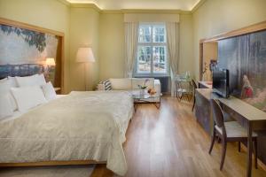 a bedroom with a bed and a desk and a television at Chateau Herálec Boutique Hotel & Spa by L'Occitane in Herálec
