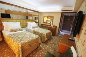 a hotel room with two beds and a television at Grand Corner Boutique Hotel in İzmir