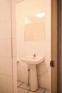 Baño blanco con lavabo y espejo en Hotel San Jose de la Montaña, en San Salvador