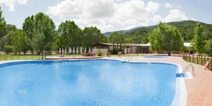 a large blue swimming pool with mountains in the background at Hotel Balneario Valle del Jerte in Valdastillas