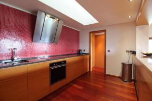 a kitchen with a sink and a red tile wall at Casa dos Cinco - Gerês in Terras de Bouro