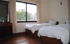 two beds in a room with a window and a room with two beds at Avalon House in Kathmandu