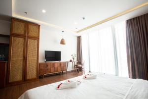 a hotel room with a bed and a television at Luu Ngai Condotel Quy Nhon in Quy Nhon