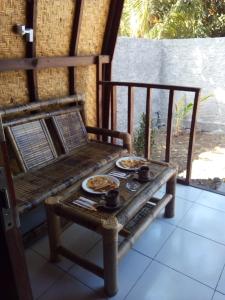 two plates of food sitting on a table on a porch at Bale Hostel in Kuta Lombok