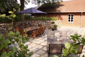 eine Terrasse mit einem Tisch, Stühlen und einem Sonnenschirm in der Unterkunft Motel Højmølle Kro in Eskilstrup