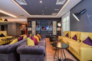 una sala de estar con sofás, mesas y sillas en Premier Inn Dubai Investments Park, en Dubái