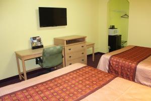 um quarto de hotel com duas camas e uma secretária e uma televisão em Hutchinson Inn em Hutchinson