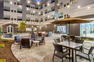 an outdoor patio with tables and chairs and an umbrella at Cambria Hotel Davenport Quad Cities in Bettendorf