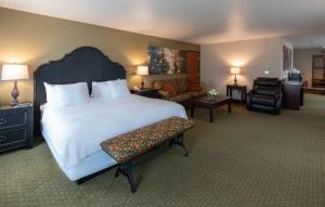 una habitación de hotel con una cama grande y una silla en Gold Miners Inn Grass Valley, Ascend Hotel Collection, en Grass Valley
