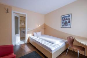 a bedroom with a bed and a desk and a chair at Hotel Lüneburg Süd in Melbeck