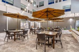 a restaurant with tables and chairs with umbrellas at Cambria Hotel Davenport Quad Cities in Bettendorf