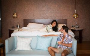 
a woman and a man laying on a bed at Raffles Seychelles in Baie Sainte Anne
