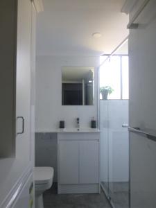 a white bathroom with a toilet and a mirror at Sun & Surf Aldinga Beach Apartment in Aldinga Beach