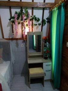 a bathroom with a vanity with a mirror and flowers at Mirna Homestay in Gili Islands