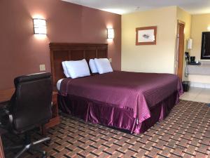 ein Hotelzimmer mit einem Bett und einem Stuhl in der Unterkunft Americas Best Value Inn-Indianola in Indianola