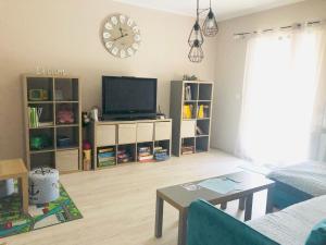 a living room with a tv and a clock on the wall at Villa Casa Mia in Balatonlelle