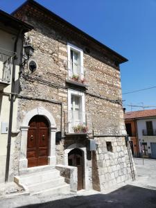 ein altes Steingebäude mit zwei Fenstern und einer Tür in der Unterkunft Le dimore del Mercante in Luco neʼ Marsi