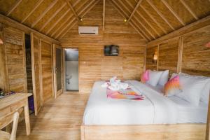 een slaapkamer met een groot wit bed en houten wanden bij Pi Karya Beach in Nusa Penida