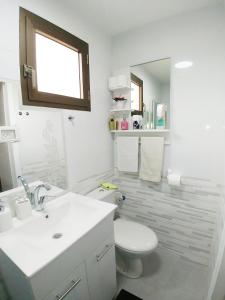La salle de bains blanche est pourvue de toilettes et d'un lavabo. dans l'établissement Carmela House, à Arad