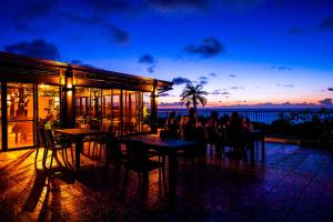 restauracja ze stołami i krzesłami oraz widokiem na ocean w obiekcie The Peridot Smart Hotel Tancha Ward w mieście Onna