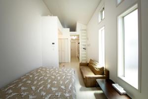 a bedroom with a bed and a couch and a window at Soshigaya Apartment in Kamatachō