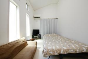 a white bedroom with a bed and a couch at Soshigaya Apartment in Kamatachō