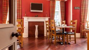 una sala da pranzo con tavolo e TV sopra il camino di Eildon Guest House a Inverness