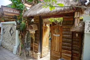 an entrance to a wooden building with a thatched door at Pondok Kana And Hostel by Ecommerceloka in Nusa Penida