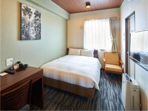 福岡市にあるワンズホテル福岡のベッドとデスクが備わる小さなホテルルームです。