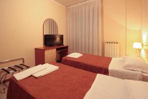 a hotel room with two beds and a television at Hotel Rose&Crown in Correggio