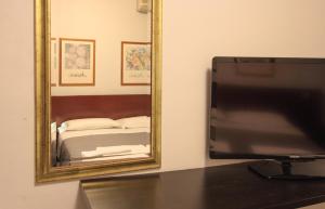 une télévision assise sur une table devant un miroir dans l'établissement Hotel Rose&Crown, à Correggio