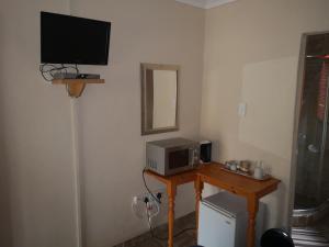 Marietjies Guesthouse في Ulundi: غرفة مع تلفزيون وطاولة مع ميكروويف
