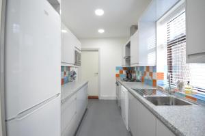 una cocina con armarios blancos y fregadero en Lexicon House - 4 bedrooms 3 bathrooms en Stoke on Trent