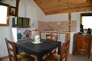 a kitchen with a black table with chairs and a television at Les Divines Cascades in Roquefort-les-Cascades +9 photos