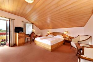 a bedroom with a bed and a desk and a television at Hotel Mühle Mayer in Termeno
