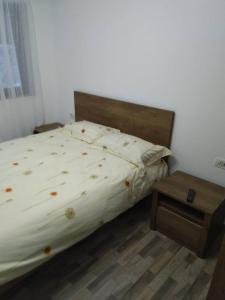 a bedroom with a bed and a wooden night stand at Pensiunea Luminita in Mustăţeşti