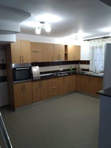 a large kitchen with wooden cabinets and a microwave at Pensiunea Luminita in Mustăţeşti