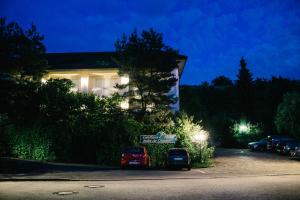 dois carros estacionados em frente a um edifício à noite em Landhaus Keller - Hotel & Restaurant em Malterdingen