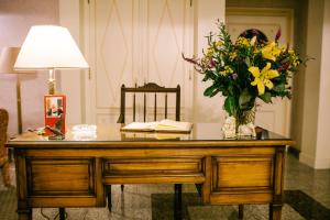 einen Schreibtisch mit einer Vase aus Blumen und einer Lampe in der Unterkunft Landhaus Keller - Hotel & Restaurant in Malterdingen