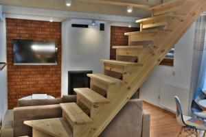 a wooden staircase in a living room with a couch and a tv at Domek - Apartament Marynarski z Kominkiem in Ustka
