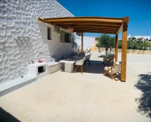 eine Terrasse mit einer Steinmauer und einer hölzernen Pergola in der Unterkunft Aeris in Koufonisia