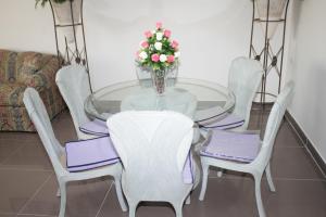 a glass table with white chairs and a vase with flowers at شقق ابراج شيراتون المنتزه in Alexandria