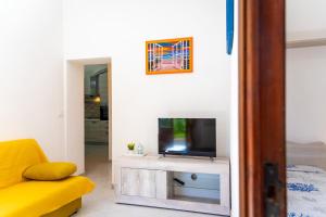 een woonkamer met een tv en een gele bank bij Villino La Fontanella in Portoferraio
