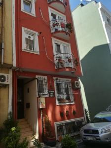 イスタンブールにあるイスタンブール アタマン スイーツの赤い建物(バルコニー付)と正面に駐車した駐車場