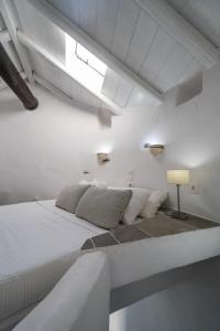 a white bedroom with a large bed and a lamp at Windmill Arades suite in Apollonia