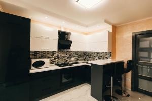 a kitchen with black cabinets and white appliances at Rika apartments in Chernivtsi +27 photos